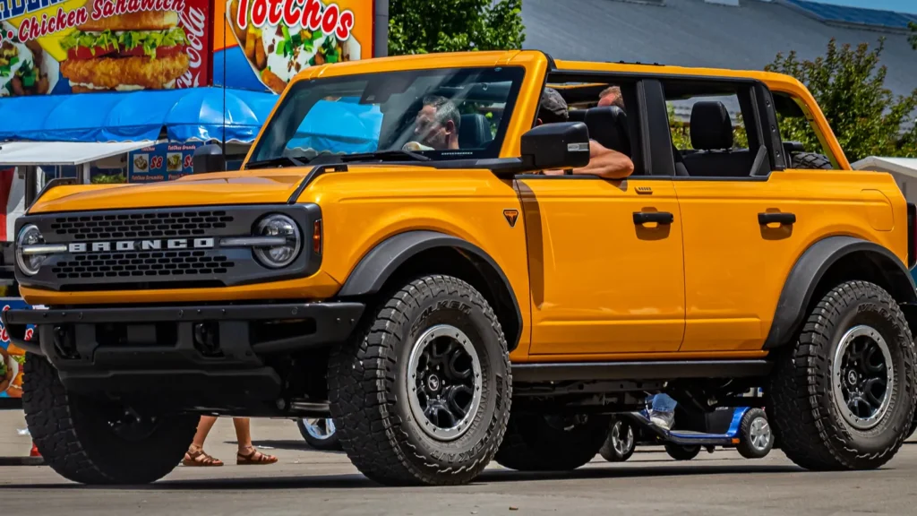 Yellow Ford Bronco driving on city roads adifferentbrian