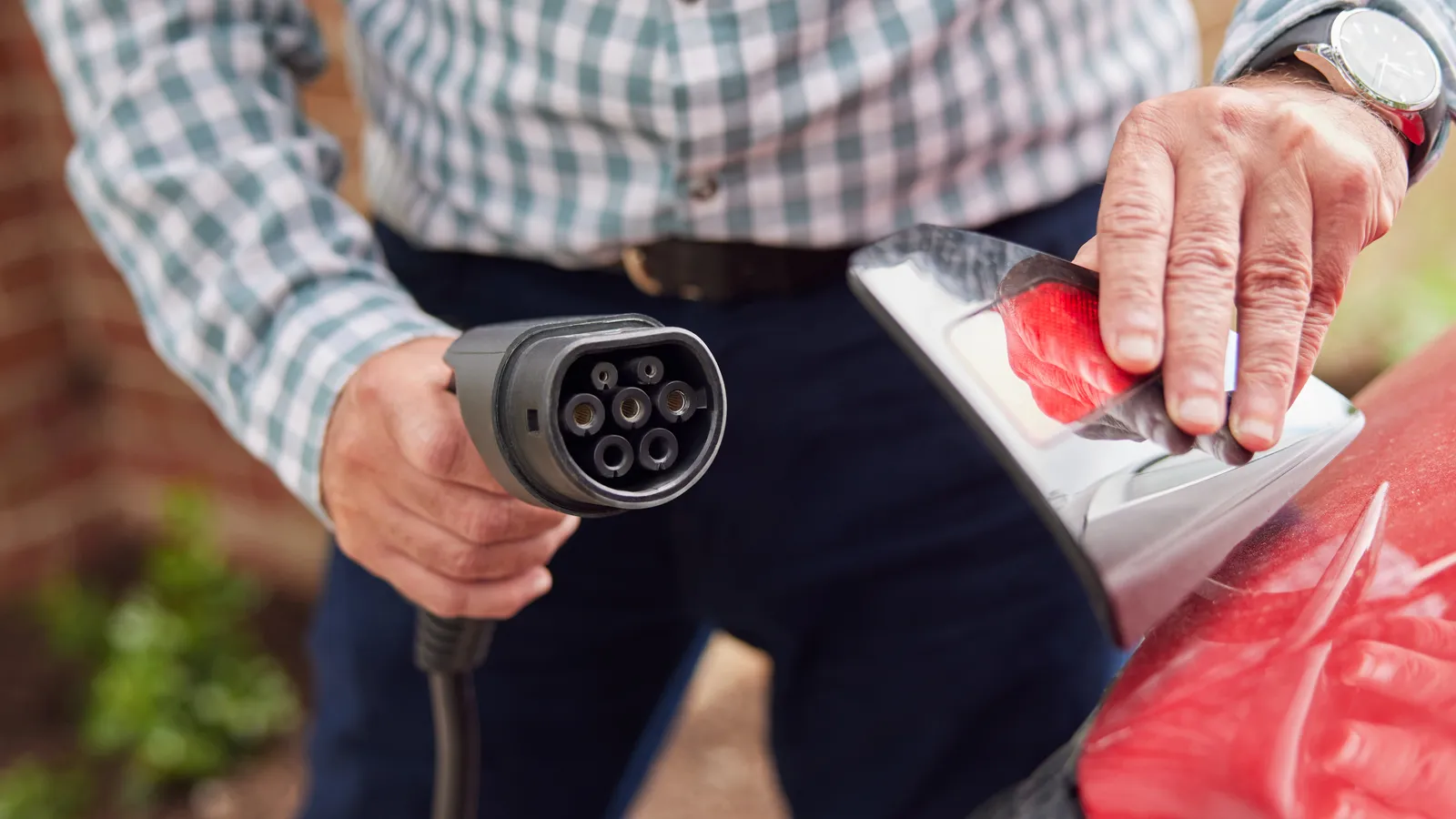 Close up of man attaching charging cable to an EV