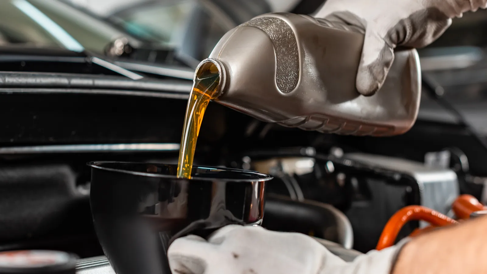 Partial view of mechanic pouring motor oil at car engine