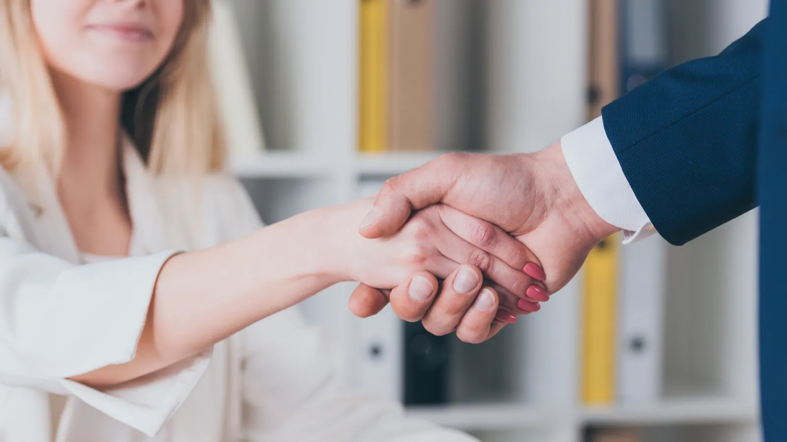 Partial view of smiling woman shaking hands with car dealer 
