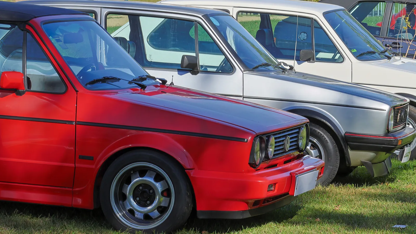 Red convertible Volkswagen Golf GTI is parked on grass