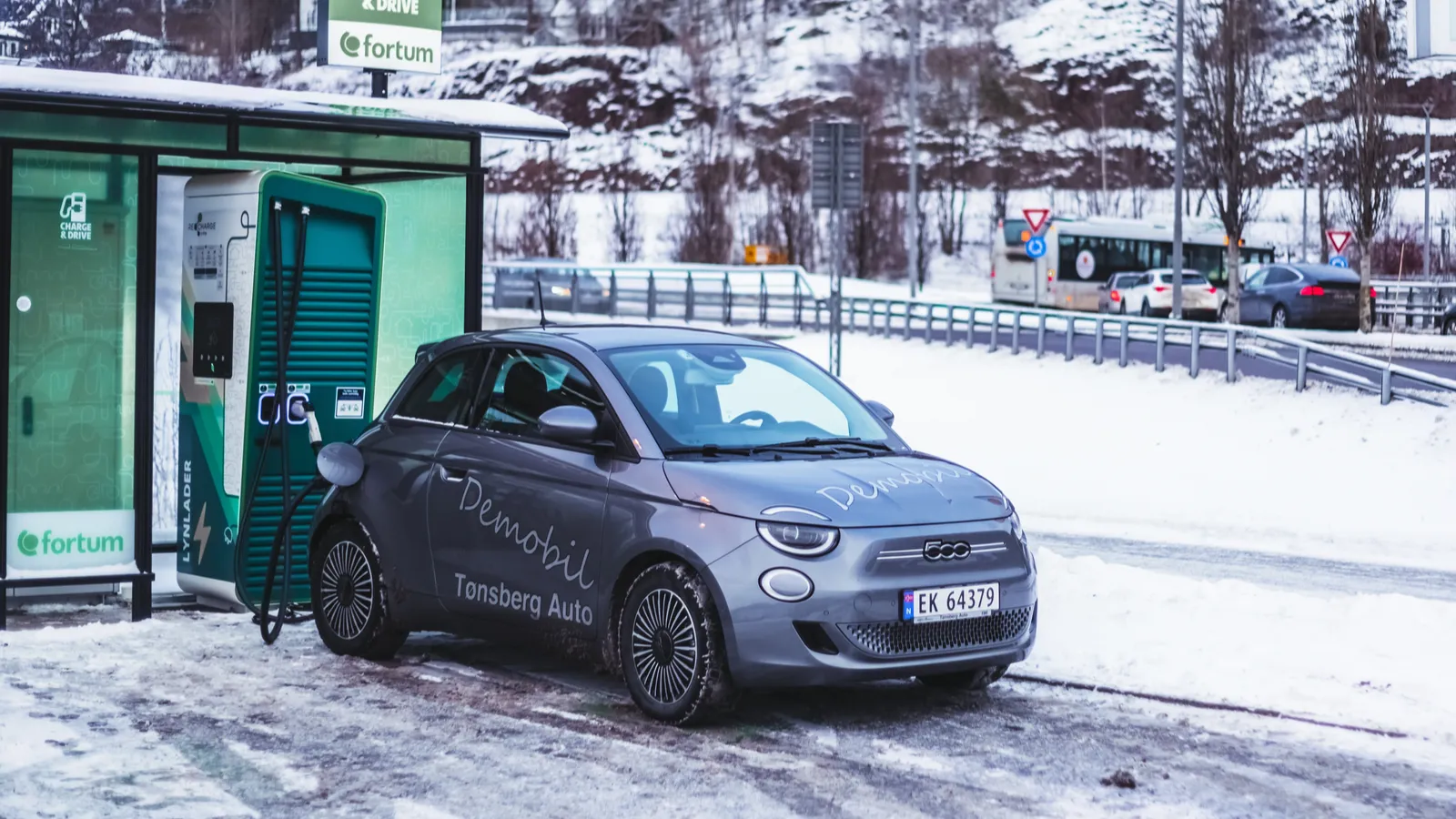Silver Fiat 500 electric charging at station in snow