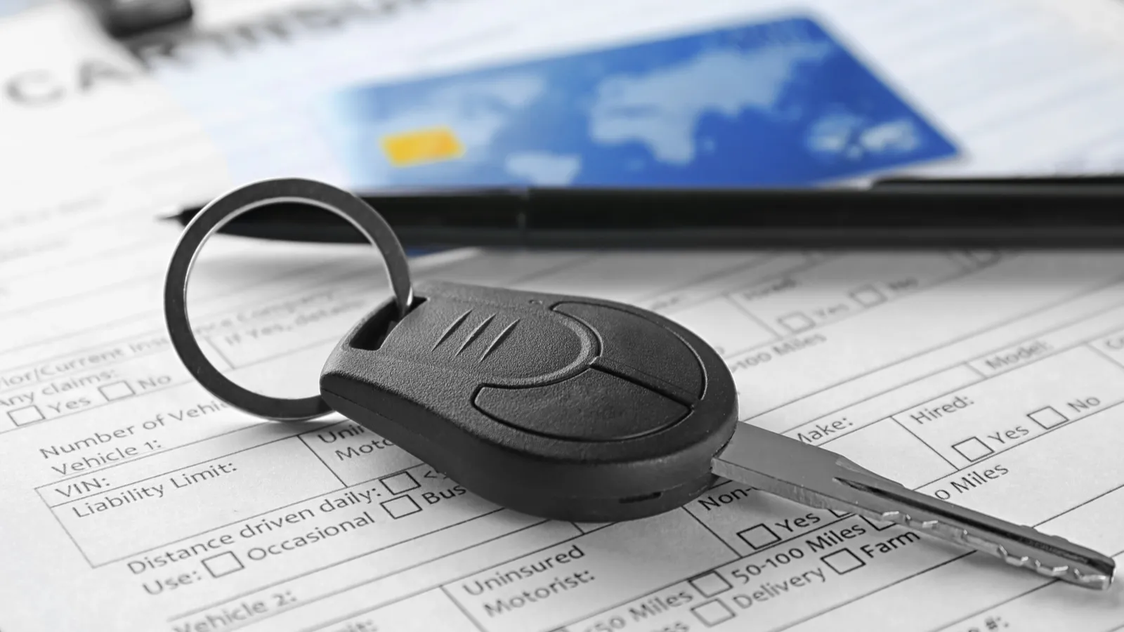 Car documents with credit card and key on table.  