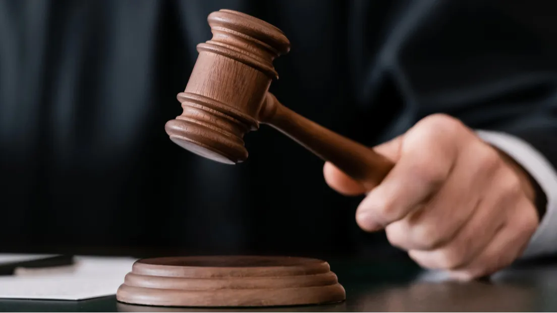 Partial view of blurred judge holding gavel during sentencing 